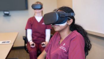 two students sitting at a table wearing VR headphones