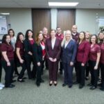 A photo of a group of people standing in a room during an open house for a new office space.