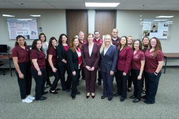 A photo of a group of people standing in a room during an open house for a new office space.